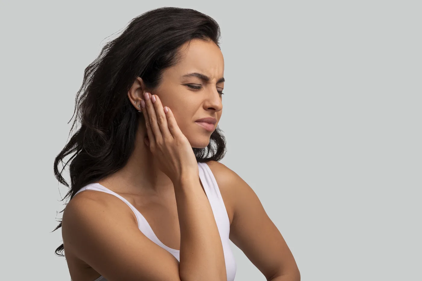 Woman touching the area near her jaw while experiencing discomfort