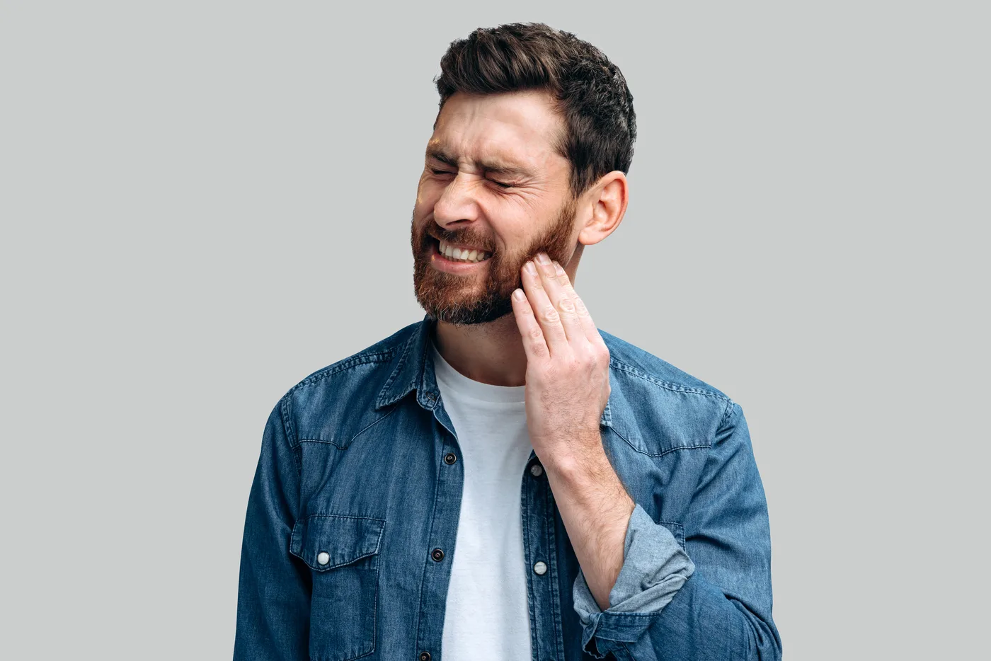 Man touching the side of his jaw while experiencing discomfort